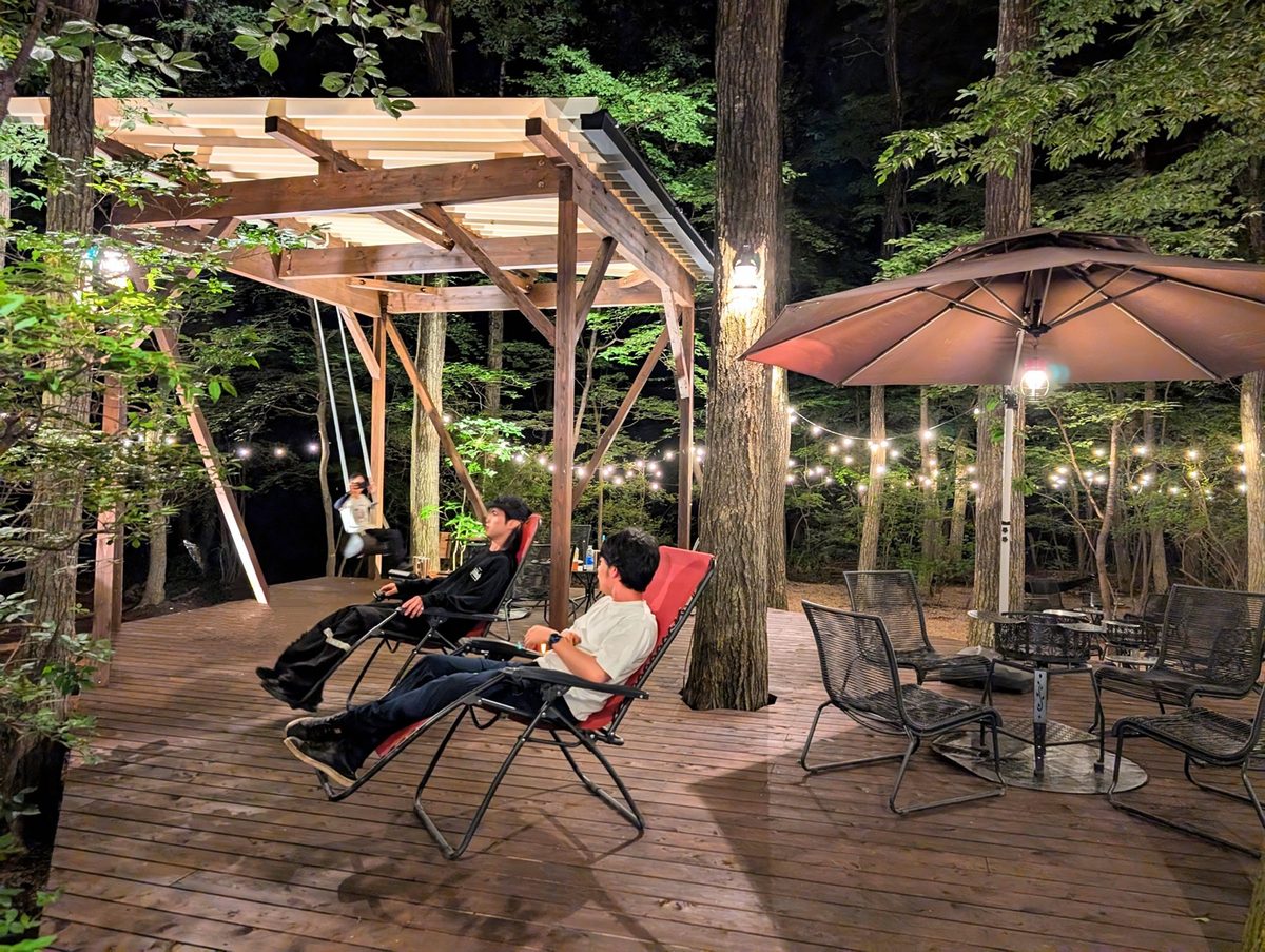 灯りのともった夕暮れのデッキでくつろぐ