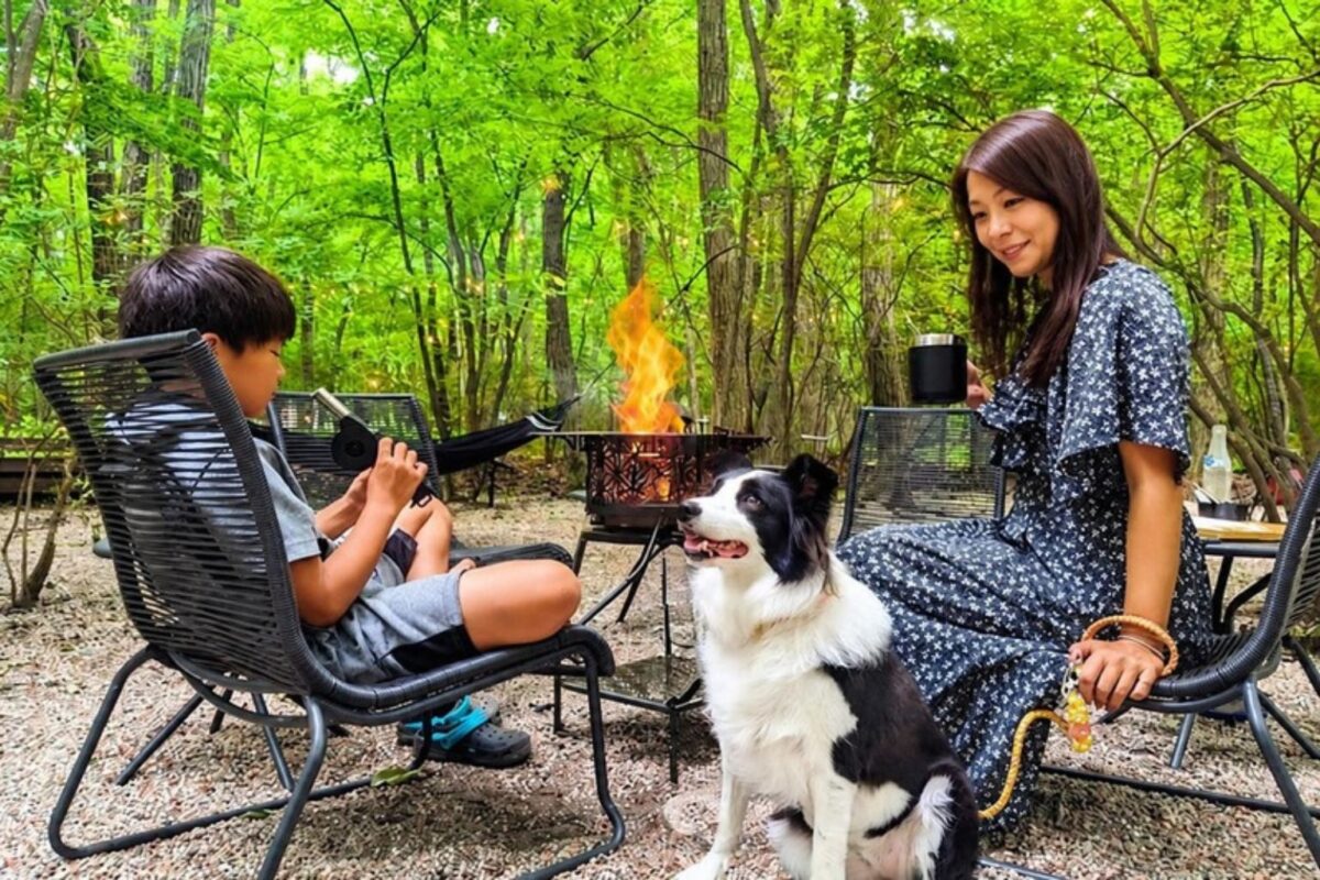 森のたき火のそばで、愛犬とくつろぐ家族